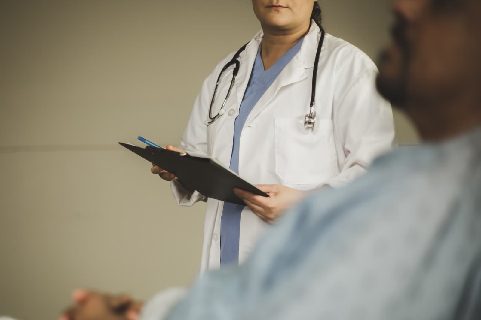 Ärztin mit Klemmbrett im Gespräch mit einem Patienten