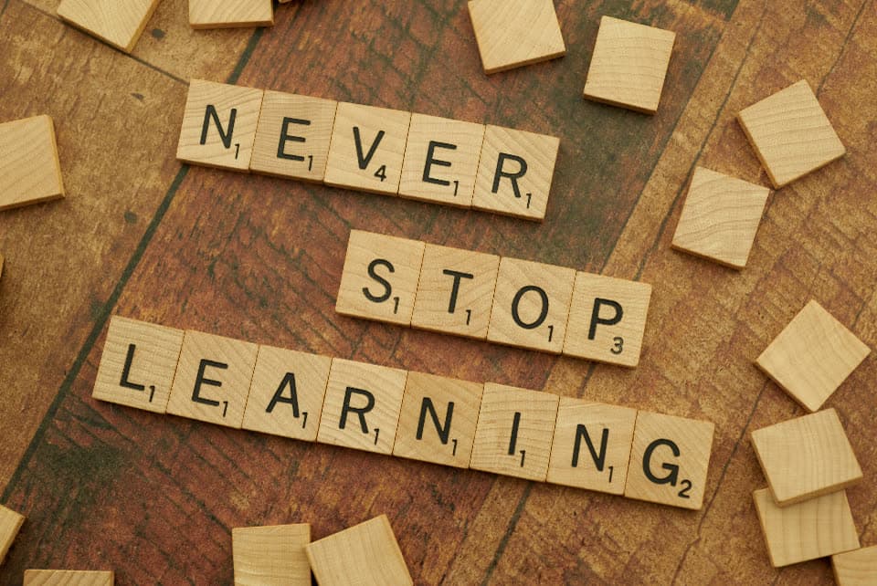 Holzbuchstaben auf einem Tisch bilden die englischen Wörter never stop learning