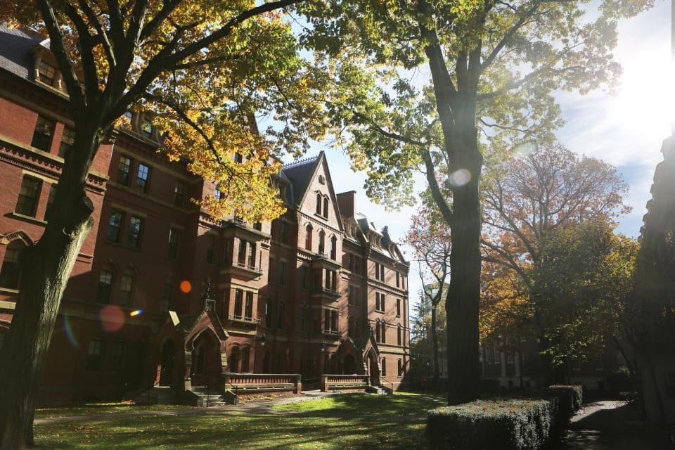 Ein altes Universitätsgebäude aus rotem Backstein hinter Herbstbäumen