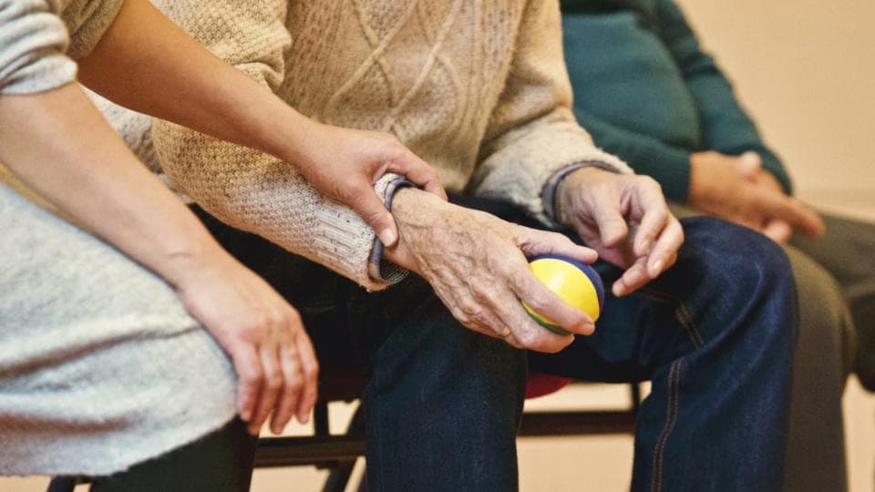 Eine jüngere Hand liegt auf dem Arm eines älteren Menschen, der einen kleinen Ball hält