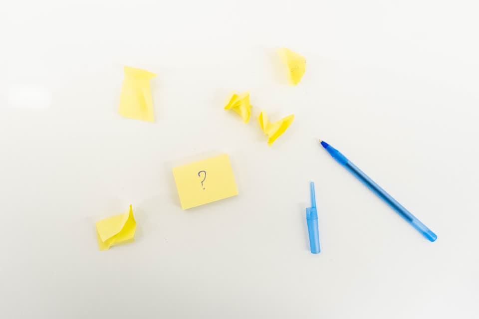 Gelbe Haftnotizen und blaue Stifte auf einer weißen Fläche