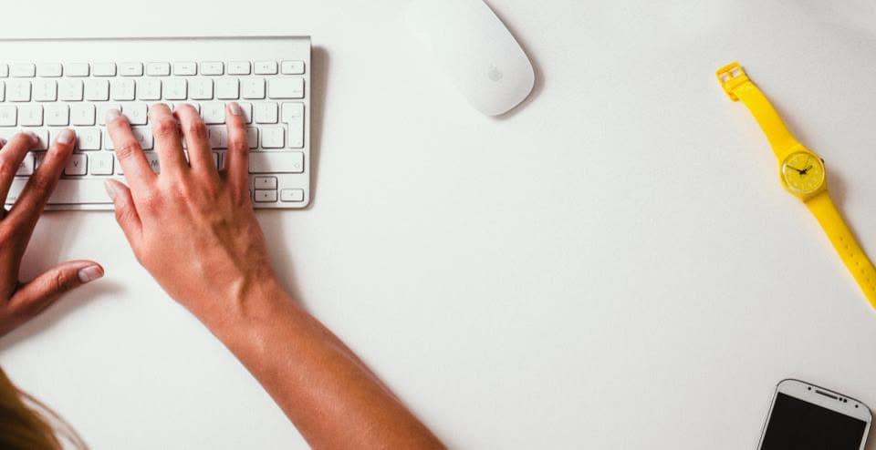 Hand auf einer weißen Tastatur neben einer Computermaus