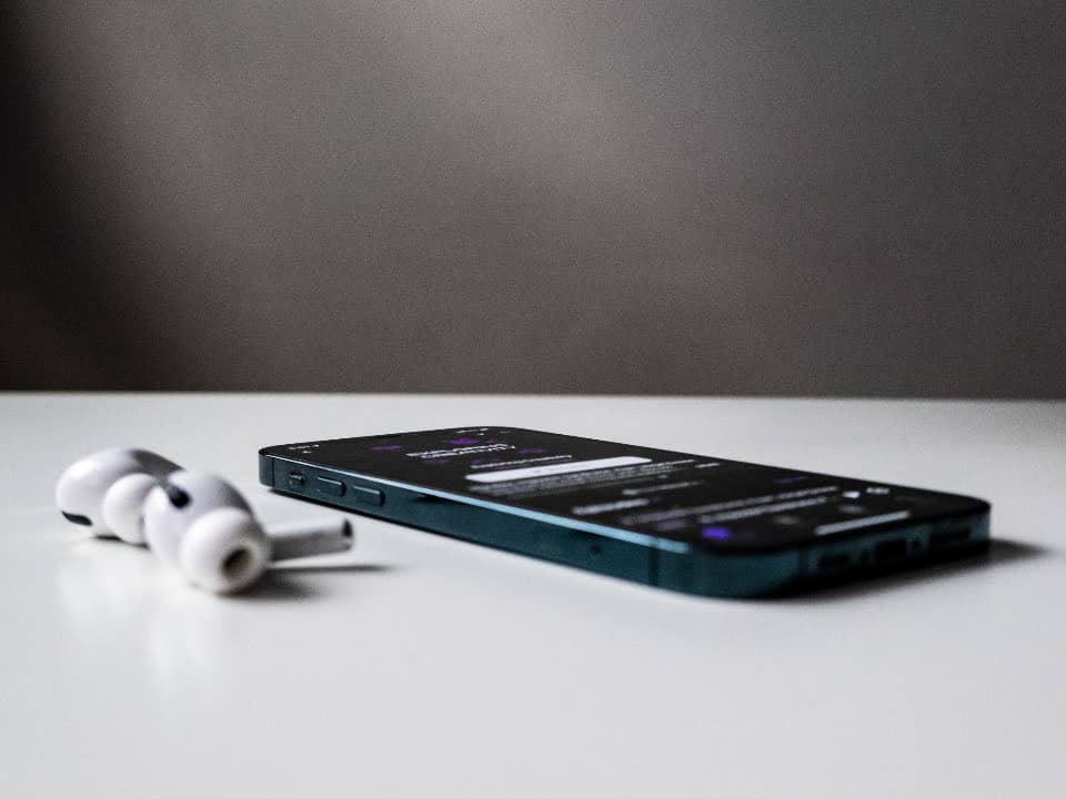 Kabellose Kopfhörer neben einem Smartphone auf einem weißen Tisch