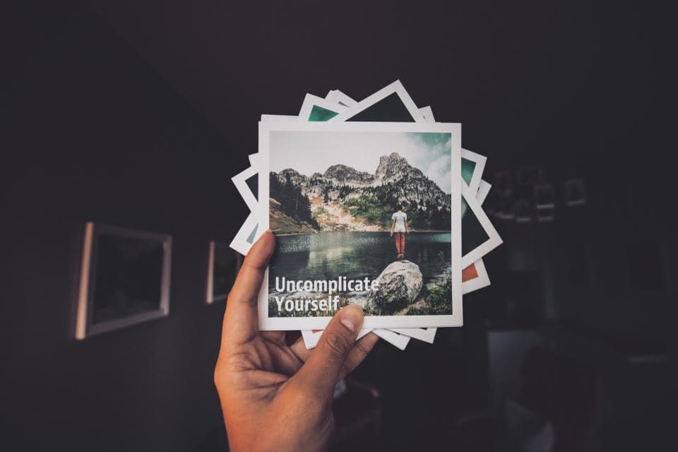 Hand hält mehrere Fotos vor einem dunklen Hintergrund