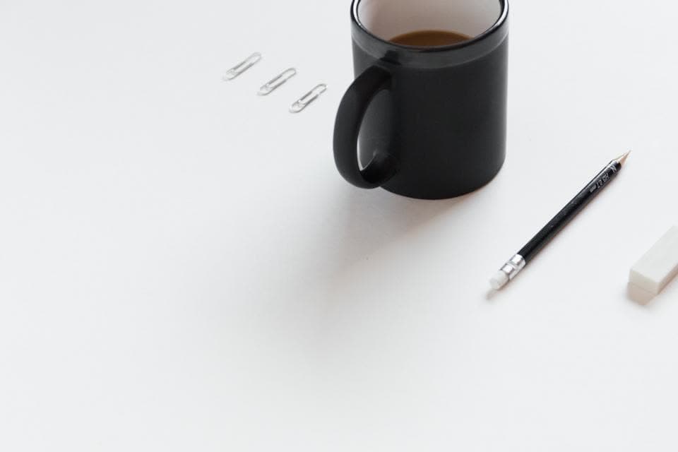 Schwarze Tasse und ein Kugelschreiber auf einem weißen Tisch