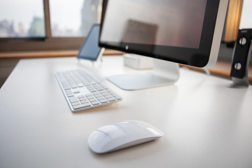 Computer mit Tastatur und Maus auf einem weißen Schreibtisch