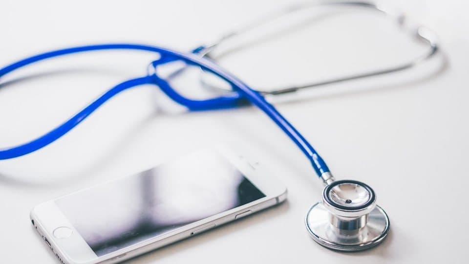 A stethoscope next to a smartphone on a white surface